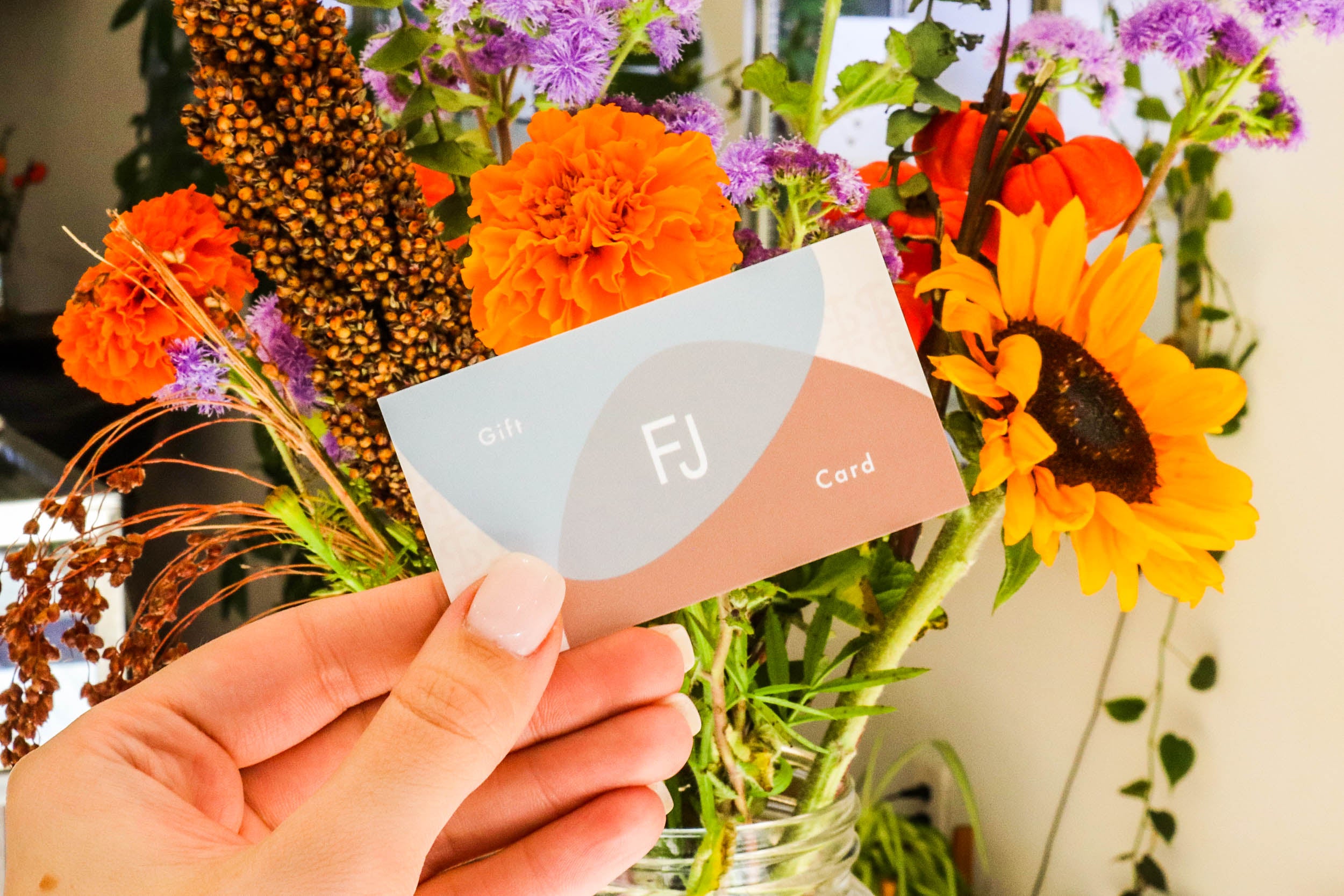 Model holds a Fitzgerald Jewelry gift card in front of a flower bouqet