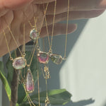 Model holds an array of pendants by Ariko featuring watermelon colored tourmalines and white diamonds